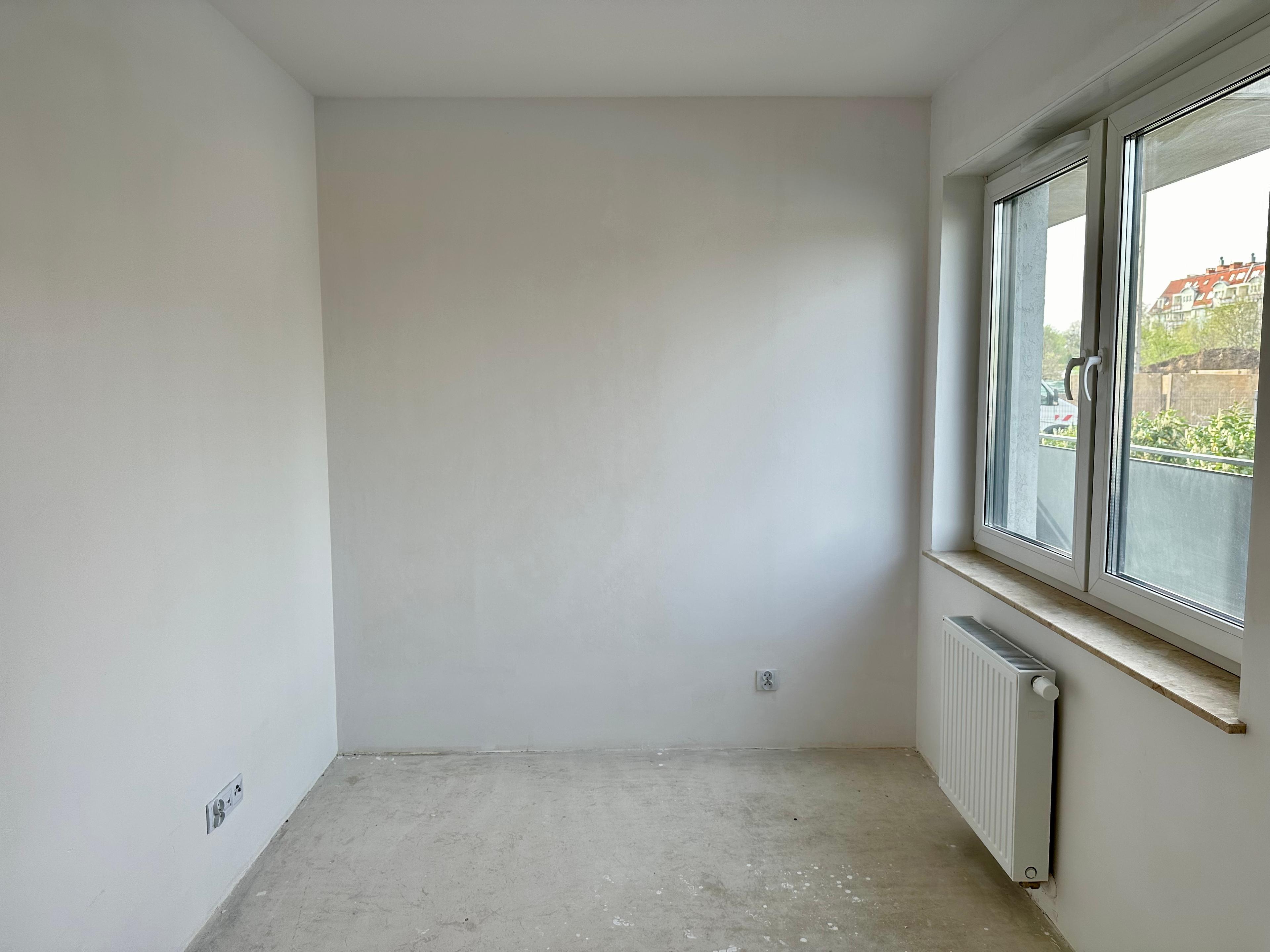 Nouvel appartement en état de développement | Chambre avec vue sur la verdure | Intérieur spacieux pour aménagement personnalisé. Chambre lumineuse avec grande fenêtre PVC et radiateur panneau. État brut fermé prêt pour une finition clé en main. Appartement moderne dans une nouvelle construction | Espace idéal pour la personnalisation. Sol en béton et murs blancs prêts pour une finition | Installations électriques et de chauffage complètes.