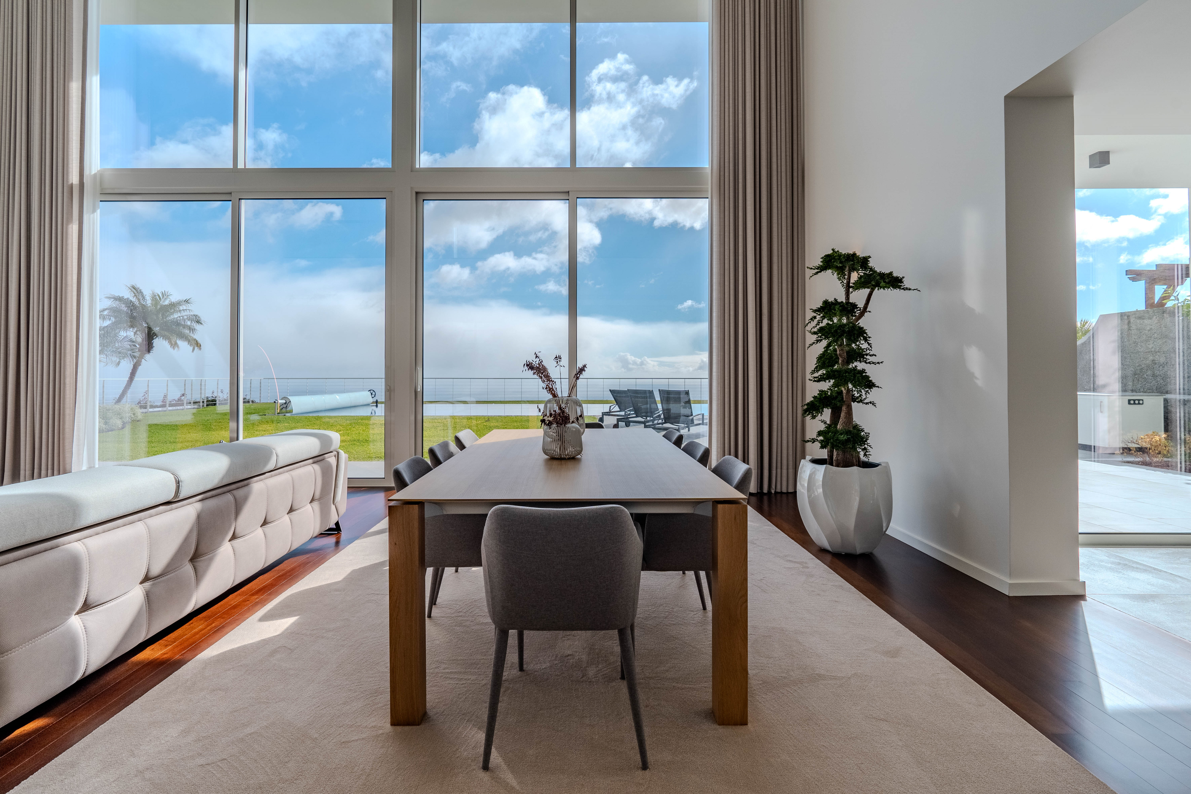 Moderne spisestue i en luksusleilighet til salgs med panoramavinduer og havutsikt. Home staging fremhever romslighet og eleganse i interiøret, noe som øker eiendommens verdi og tiltrekker potensielle kjøpere. Store glassflater gir naturlig lys, noe som er nøkkelen i strategien for boligsalg gjennom profesjonell presentasjon og fotografering av premium eiendom.