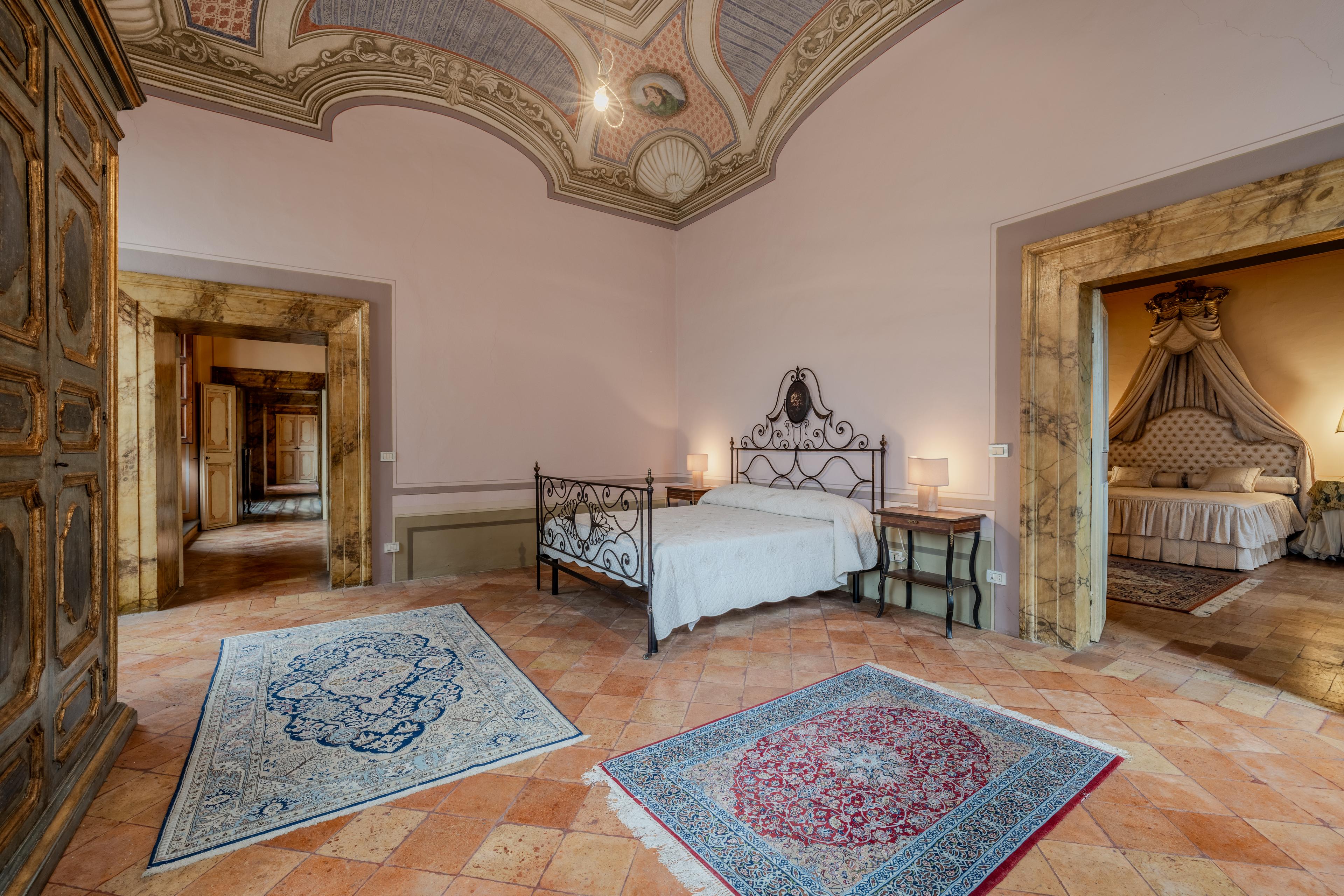 Camera da letto in una villa storica in vendita in Umbria con soffitto originale affrescato e arredamento elegante – proprietà esclusiva in Italia.