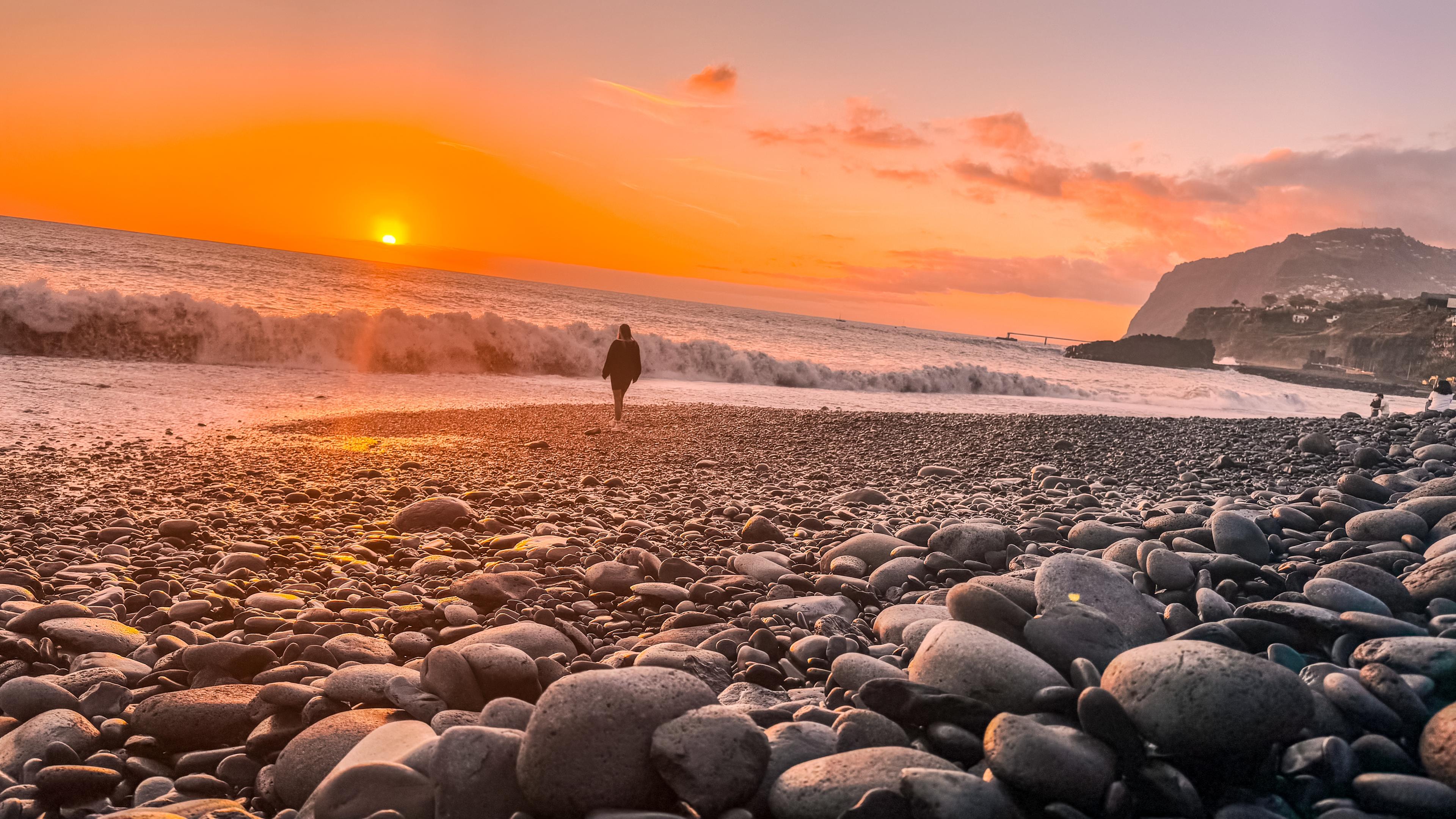 Spektakulær solnedgang på en steinete strand på Madeira med utsikt over havet og klippene. Varmt klima året rundt gjør Madeira til et ideelt sted å bo og investere i eiendom. Avslappende atmosfære, vakre landskap og eksepsjonelle værforhold.