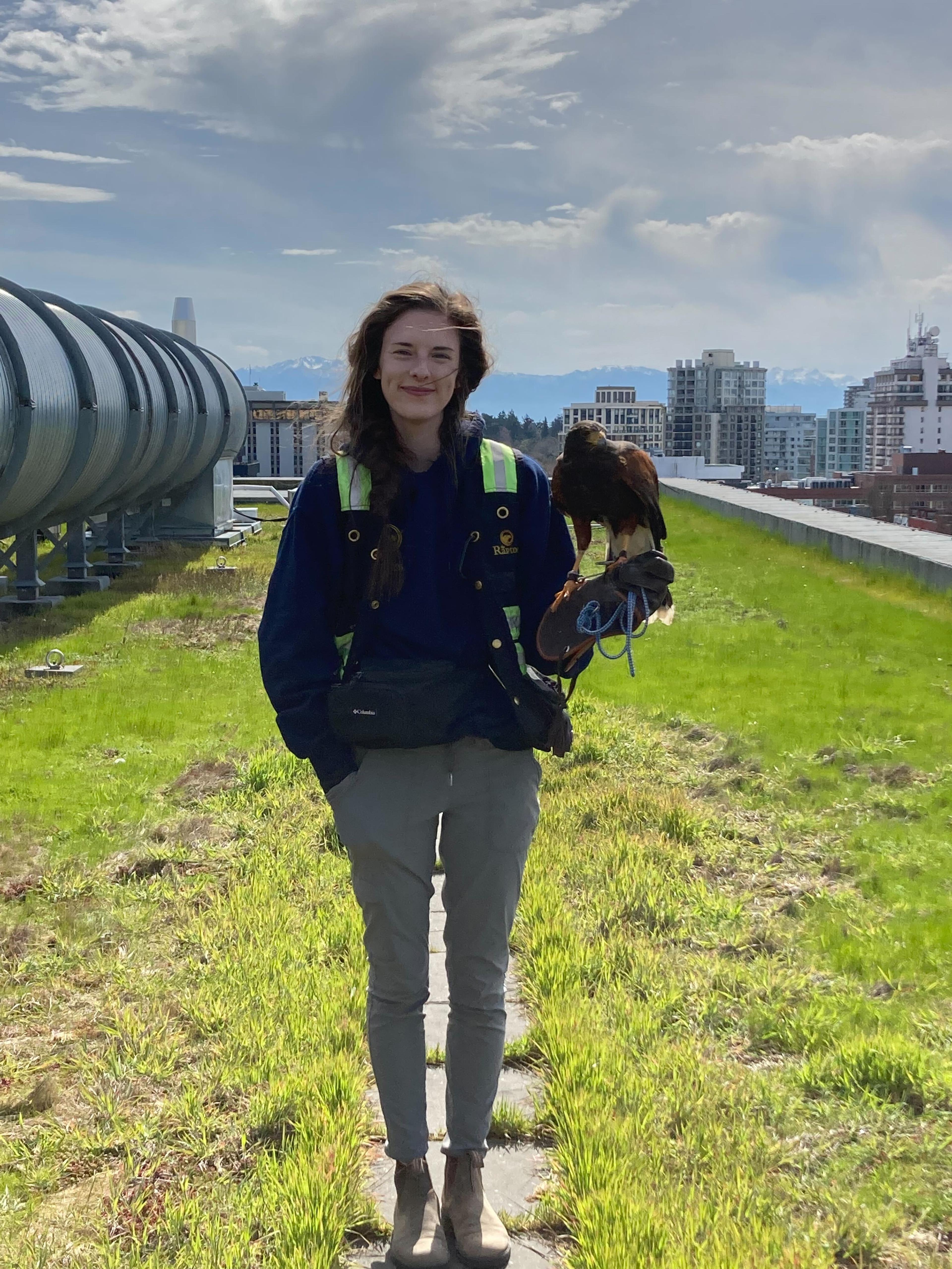 Woman stands with a hawk on her glove, on a rooftop