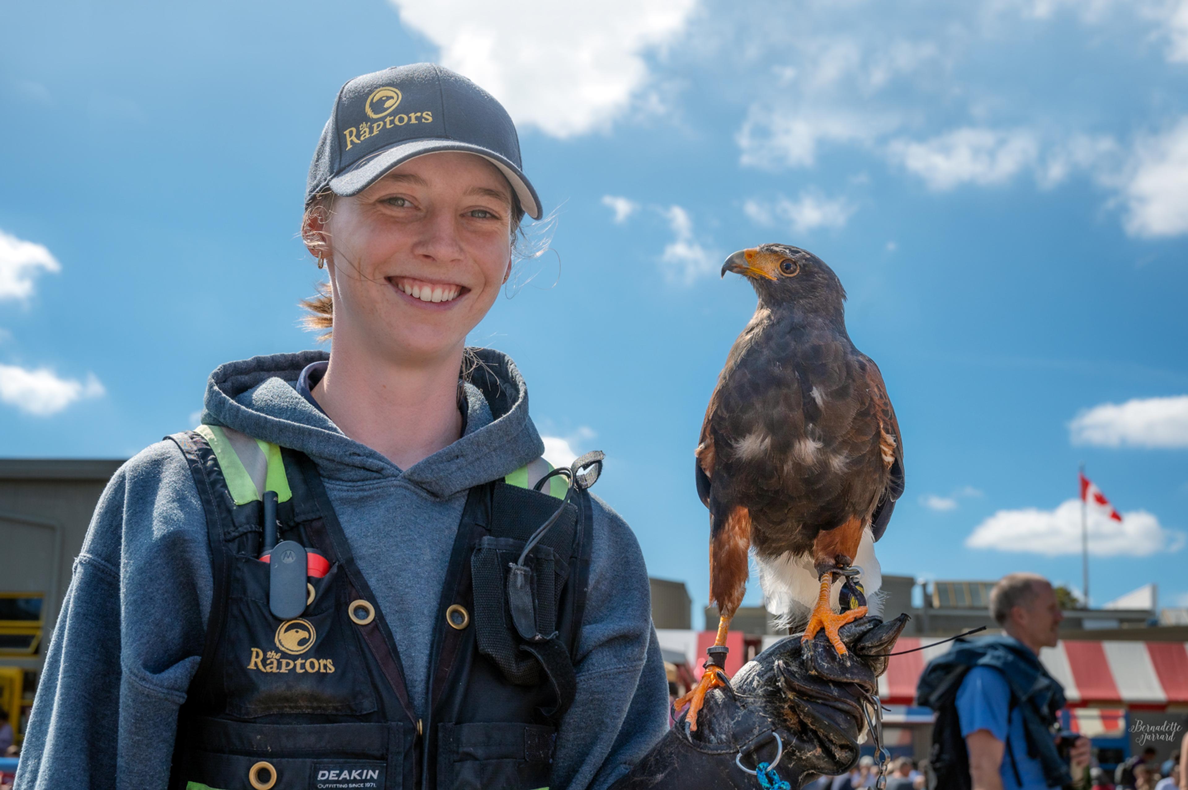 Raptors employee stands in a market with a hawk on her glove