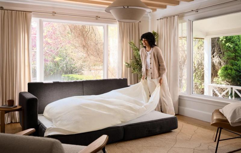 Woman making up a charcoal Span sleeper sofa pulled out into a bed