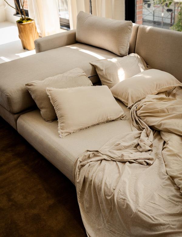Span sleeper sectional pulled out into a bed with linen bedding