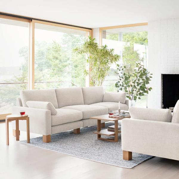 A white 3-piece sofa with an oak side table in front of large windows