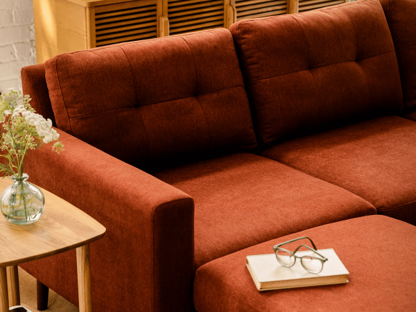 Close-up of a rust performance fabric sectional with a book and glasses on the ottoman