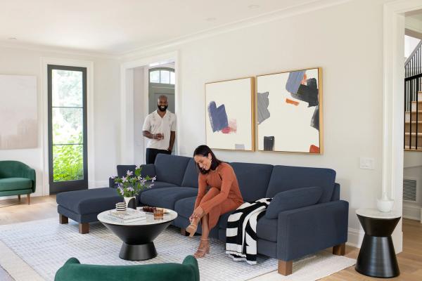 Woman sitting on a blue sofa putting her shoes on