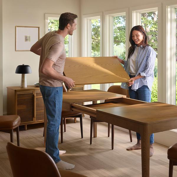 Couple assembling oak dining table in dining room