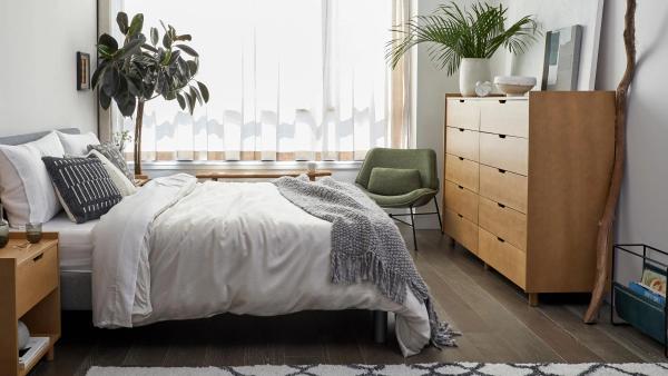 Image of a bedroom with bed, wooden dresser and wooden nightstand