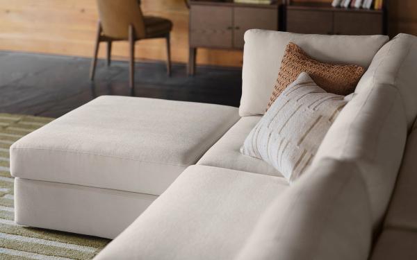 White ottoman and 3-piece sofa in front of walnut bookshelves