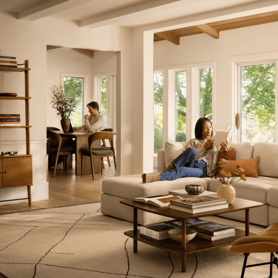 Woman reading on a cream sectional in a bright living room