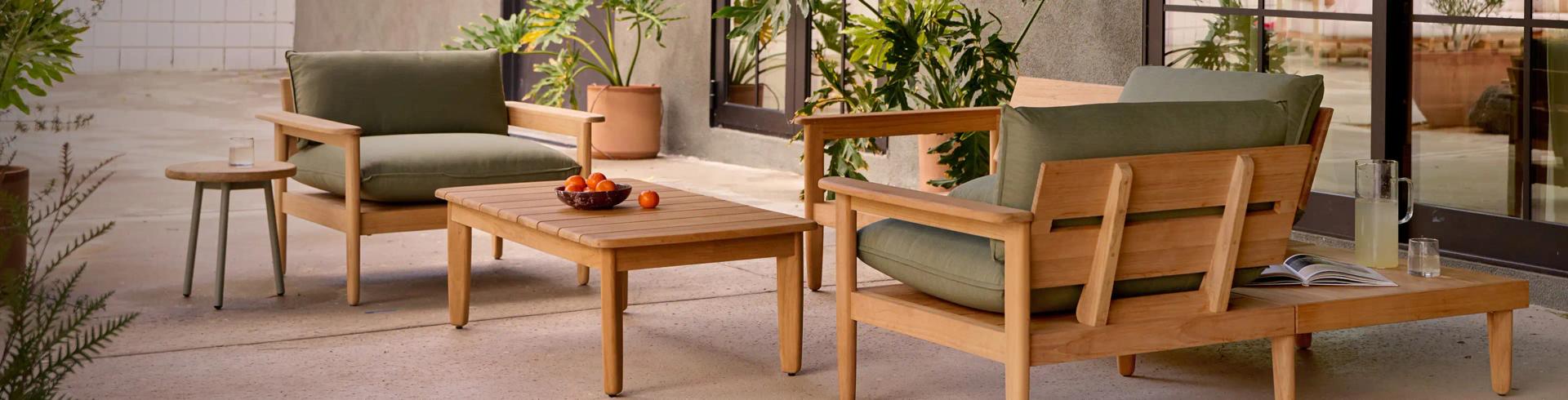 Teak outdoor furniture set with olive green cushions on modern patio with plants and large windows