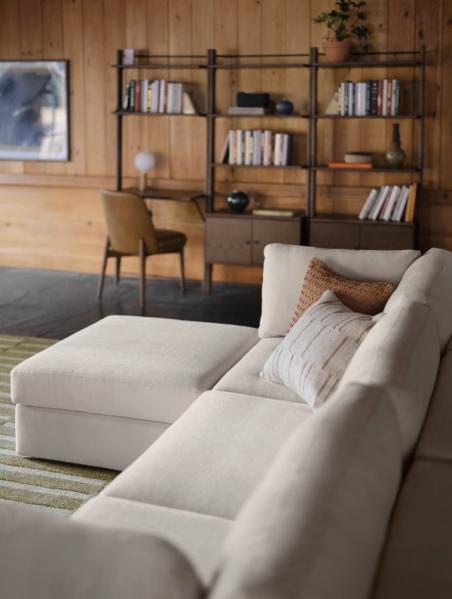 White ottoman and 3-piece sofa in front of walnut bookshelves