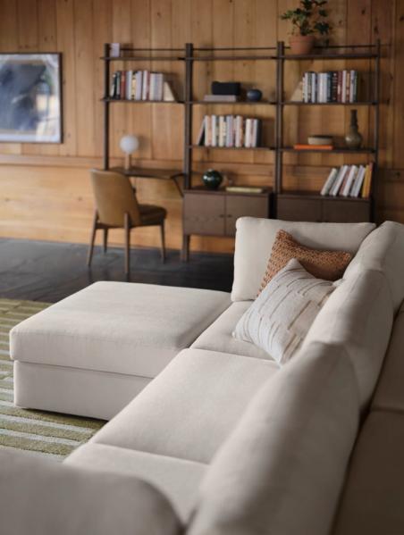 White ottoman and 3-piece sofa in front of walnut bookshelves