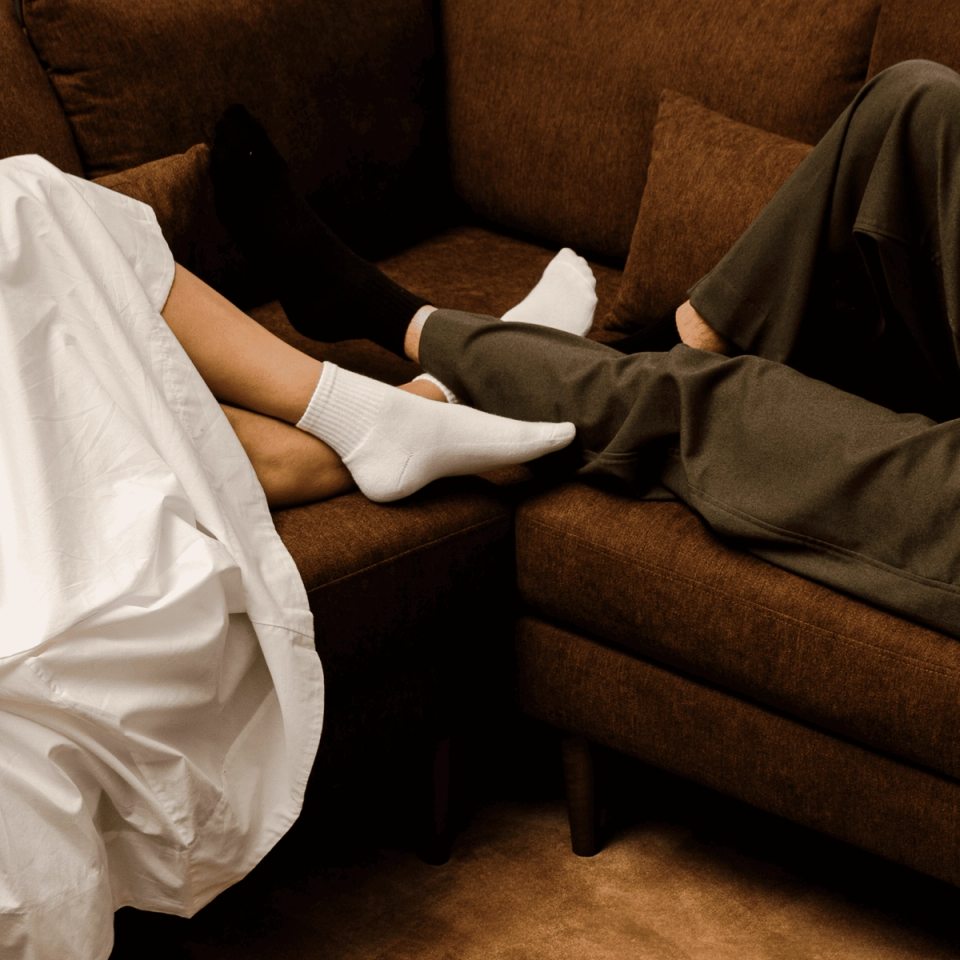 Two people lounging with their feet up on a brown fabric sofa