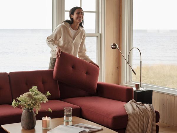 woman placing pillows on Brick Red Nomdad sectional with chaise