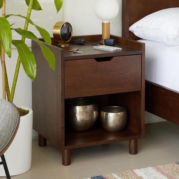 Wooden dresser with one drawer next to a bed