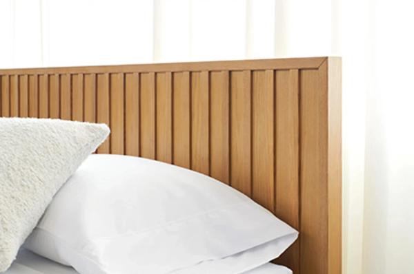 Wooden slatted headboard with white pillows and bedding in modern bedroom