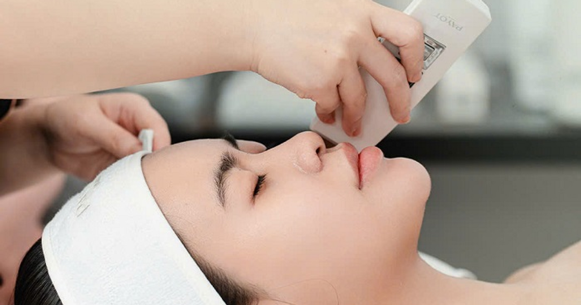 A woman receives a facial treatment using a handheld device.