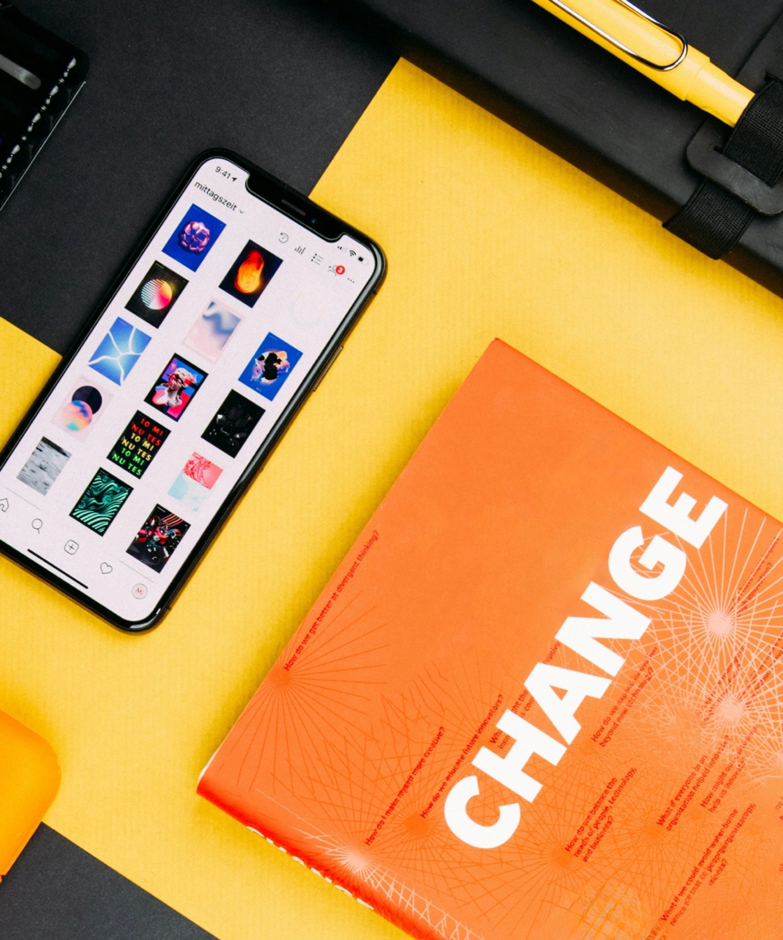 Flat lay of a phone showing an Instagram grid next to an orange magazine with bold "CHANGE" cover typography.