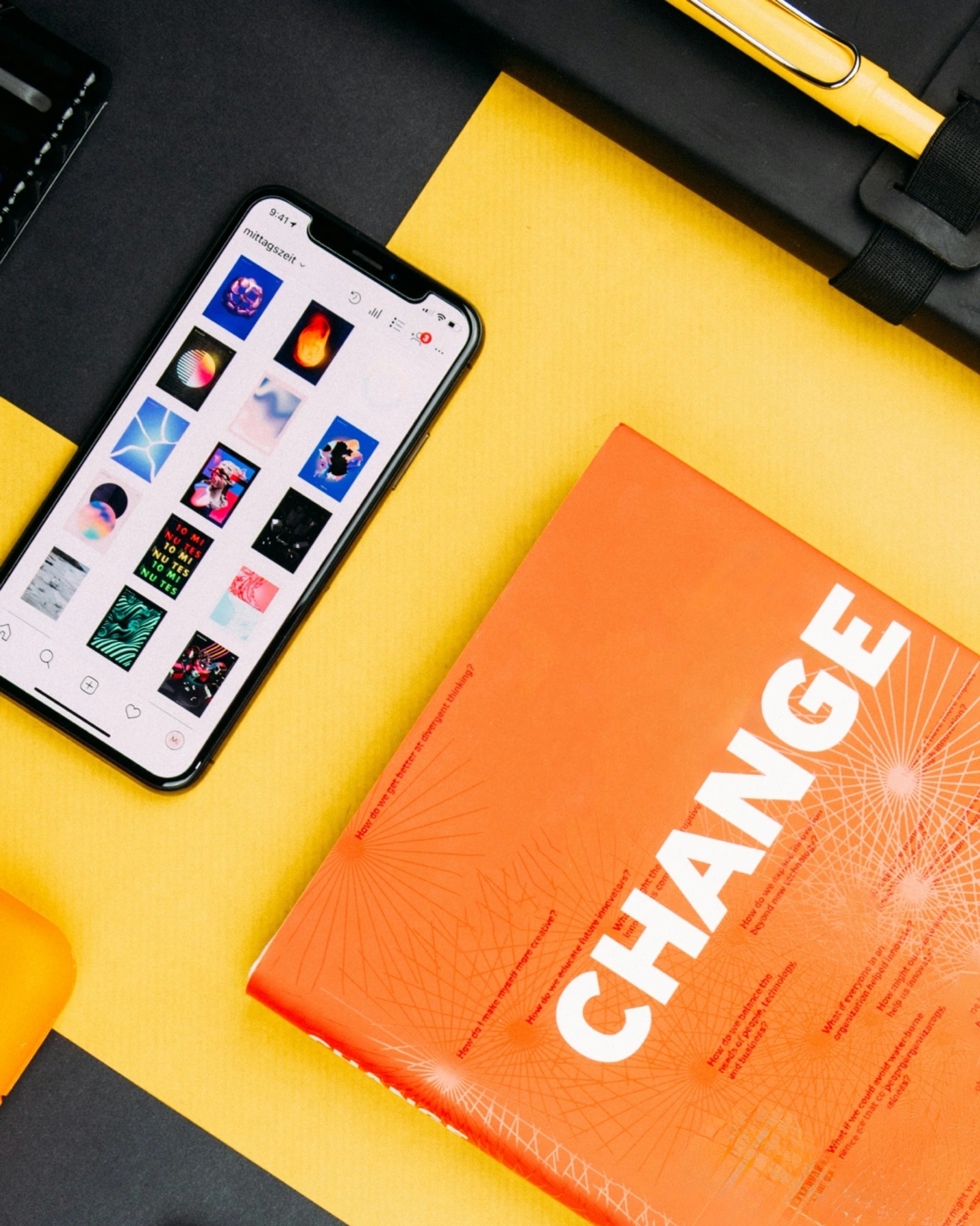 Flat lay of a phone showing an Instagram grid next to an orange magazine with bold "CHANGE" cover typography.