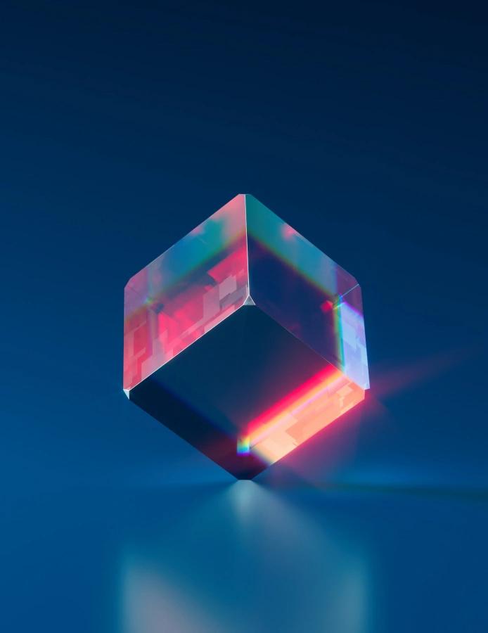 Translucent glass cube refracting pink and red light against a deep blue background.