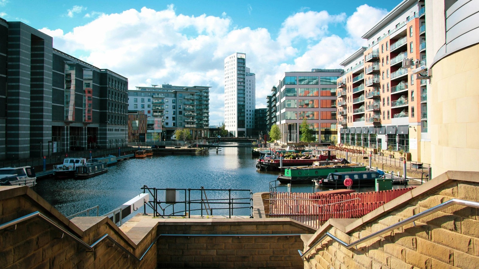 View of Leeds Dock with narrowboats moored along the waterfront and modern apartment blocks framing the marina.