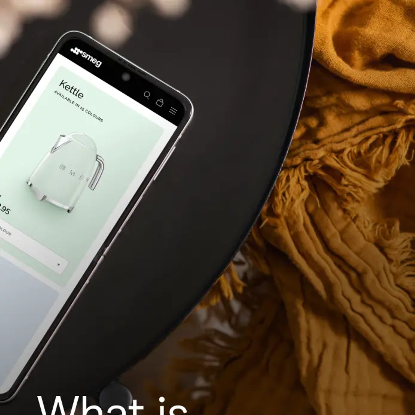 A smartphone displaying the Smeg website's kettle product page rests on a dark round table, next to a folded mustard-yellow textile. Text overlay reads: What is Optimizely?