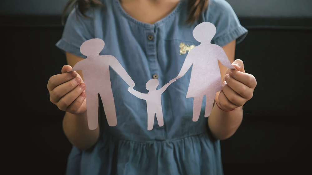 Image Paper cut-out figures of a family held in a pair of cupped hands