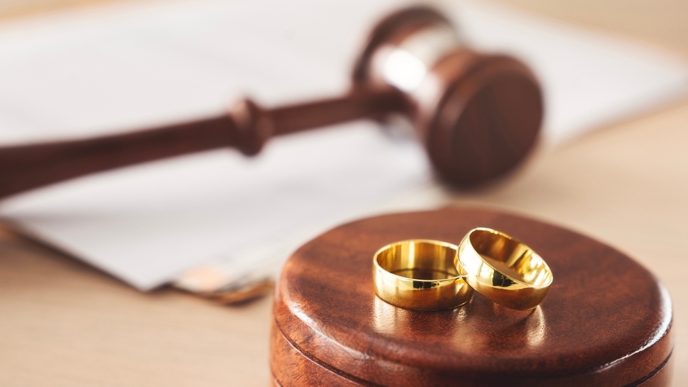 Image Two gold wedding rings beside a judge's gavel on a desk
