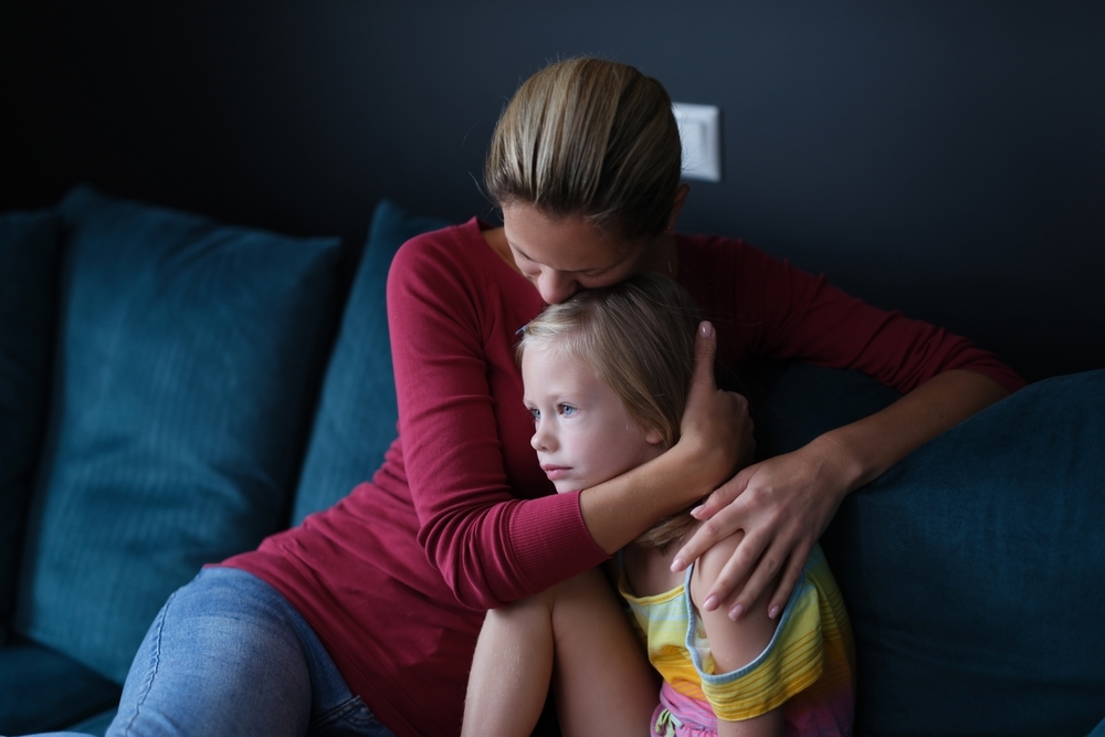 Image A parent holding a young child on a sofa