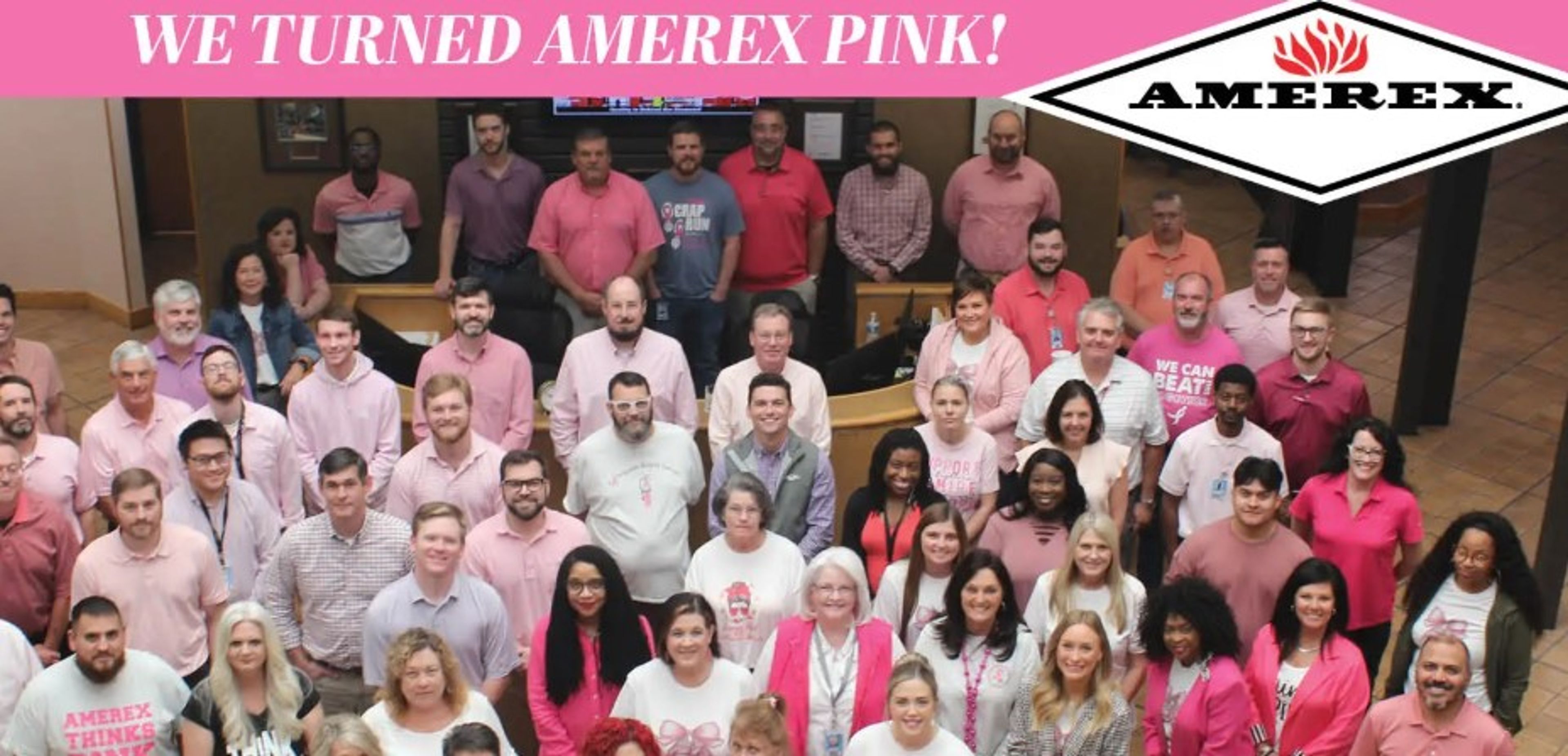 Large group of Amerex employees wearing various shades of pink pose together indoors under a banner that reads, “We turned Amerex pink!” Amerex logo is visible at the top right corner.