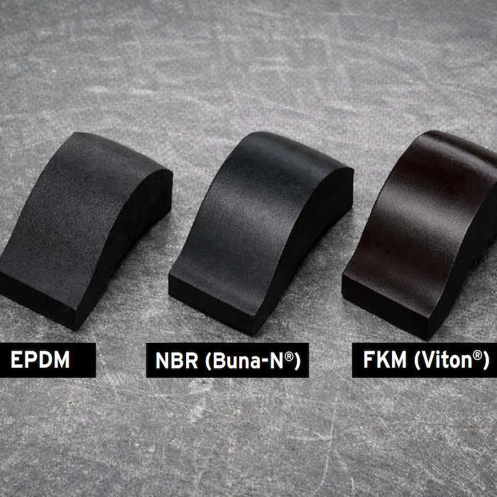 Three black rubber samples labeled EPDM, NBR (Buna-N®), and FKM (Viton®) are displayed on a gray textured surface. Each sample is curved and shown side by side for comparison.