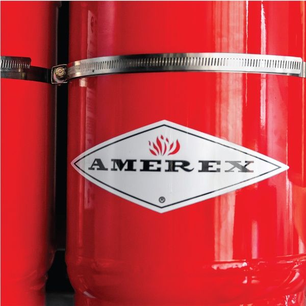 Close-up of a red fire extinguisher with a metal strap and a diamond-shaped “Amerex” logo featuring a flame symbol in the center.
