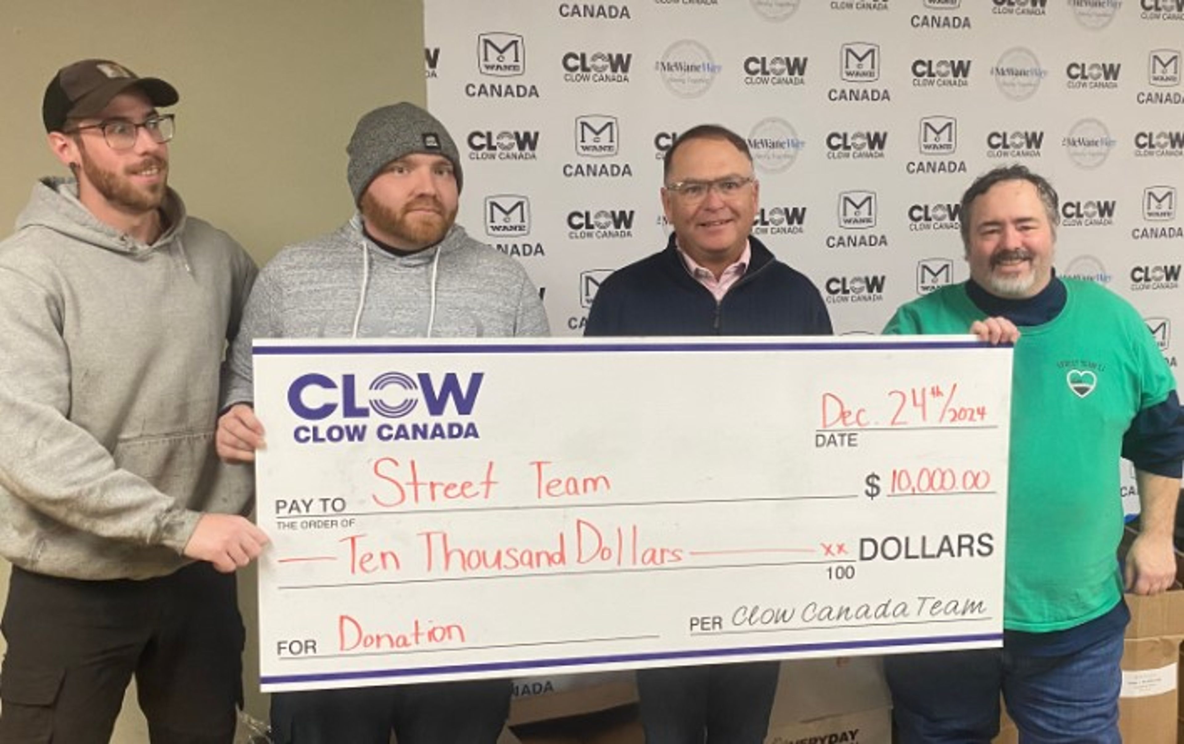 Four men stand together holding a large check for $10,000 made out to “Street Team” from Clow Canada, dated December 24, 2021. They are smiling in front of a branded Clow Canada backdrop.