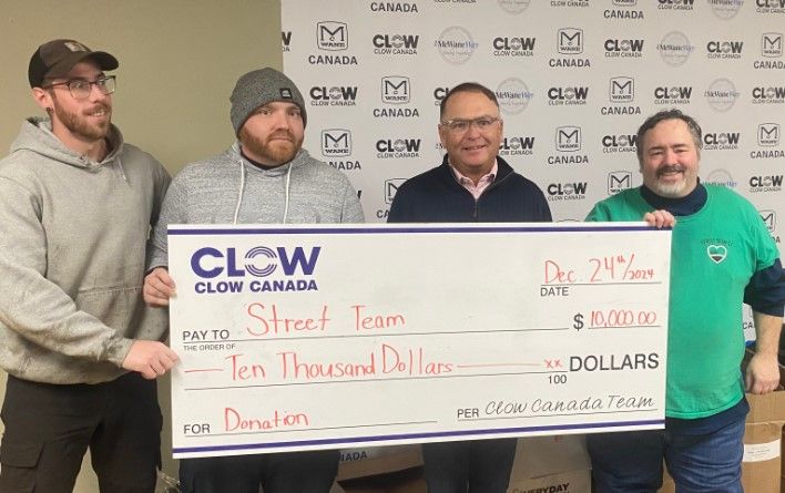 Four men stand together holding a large check for $10,000 made out to “Street Team” from Clow Canada, dated December 24, 2021. They are smiling in front of a branded Clow Canada backdrop.