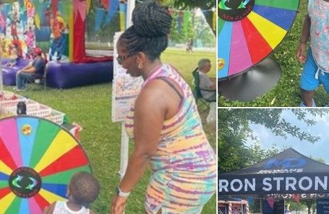 A woman and child spin a colorful prize wheel outdoors near a tent and bounce house at a fair or festival. The images show close-ups of the wheel and a tent reading “IRON STRONG.”.