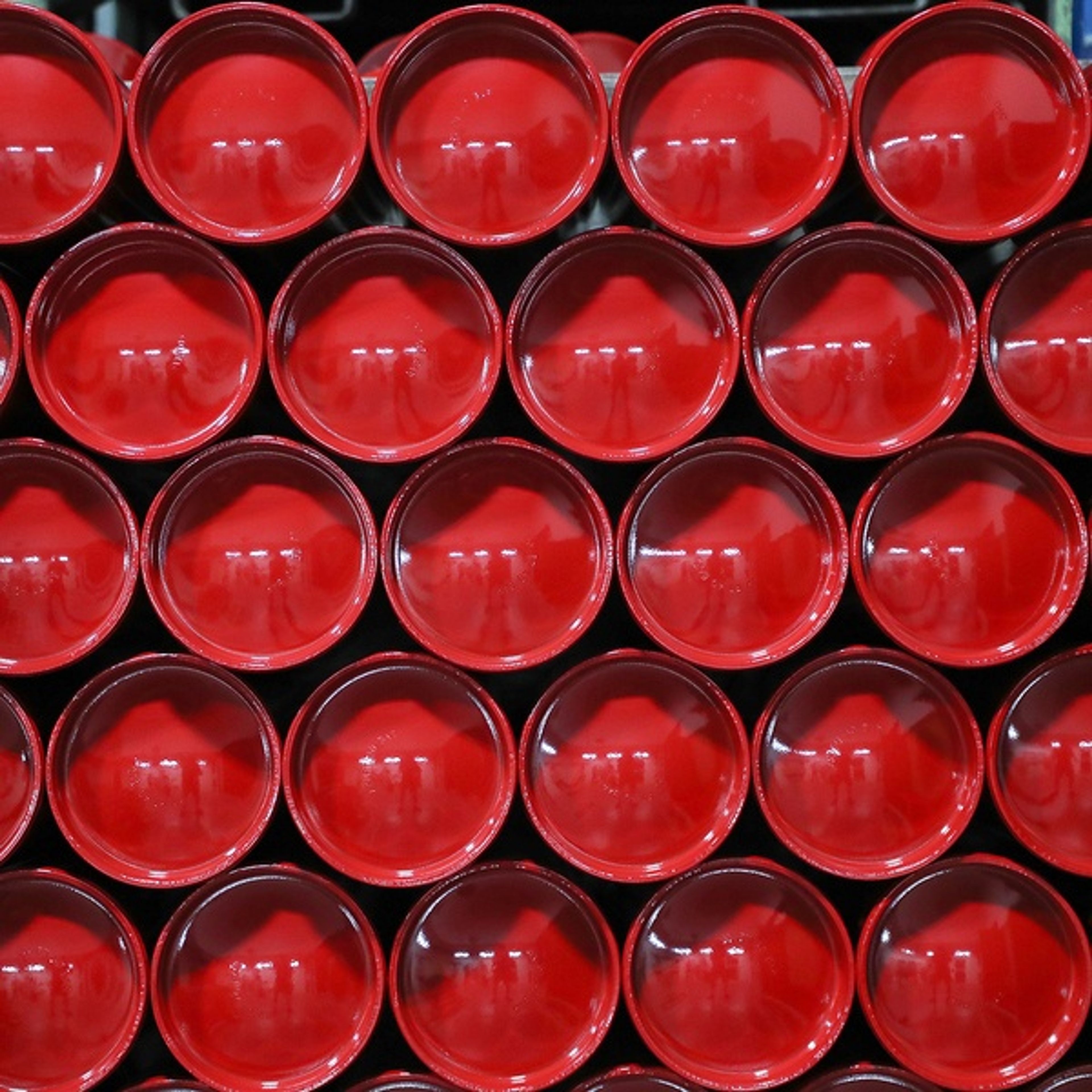 Rows of stacked, round, bright red cups viewed from above, forming a visually striking geometric pattern.
