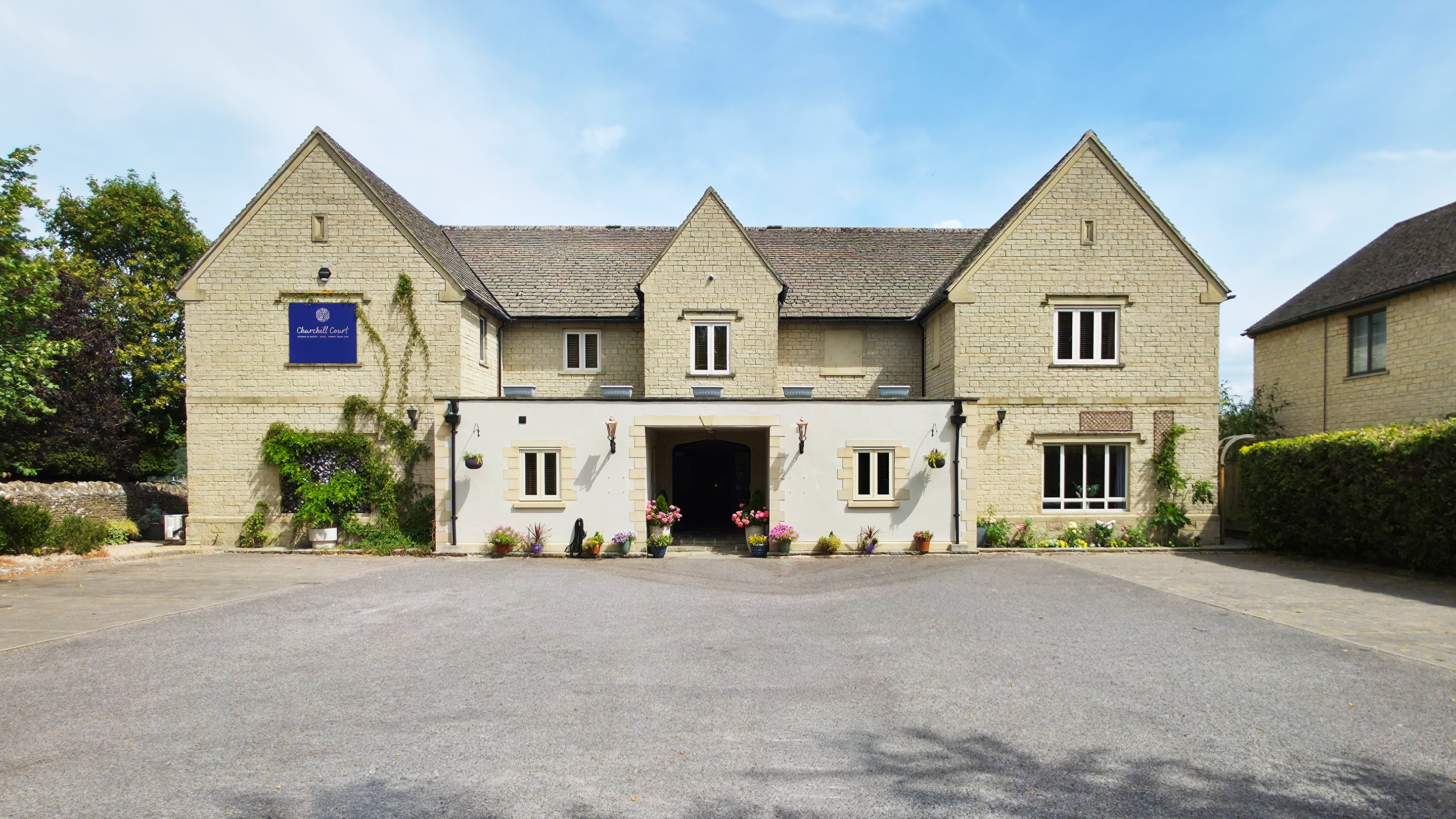 Timber gate and lamp post in front of a stone building with porch entrance