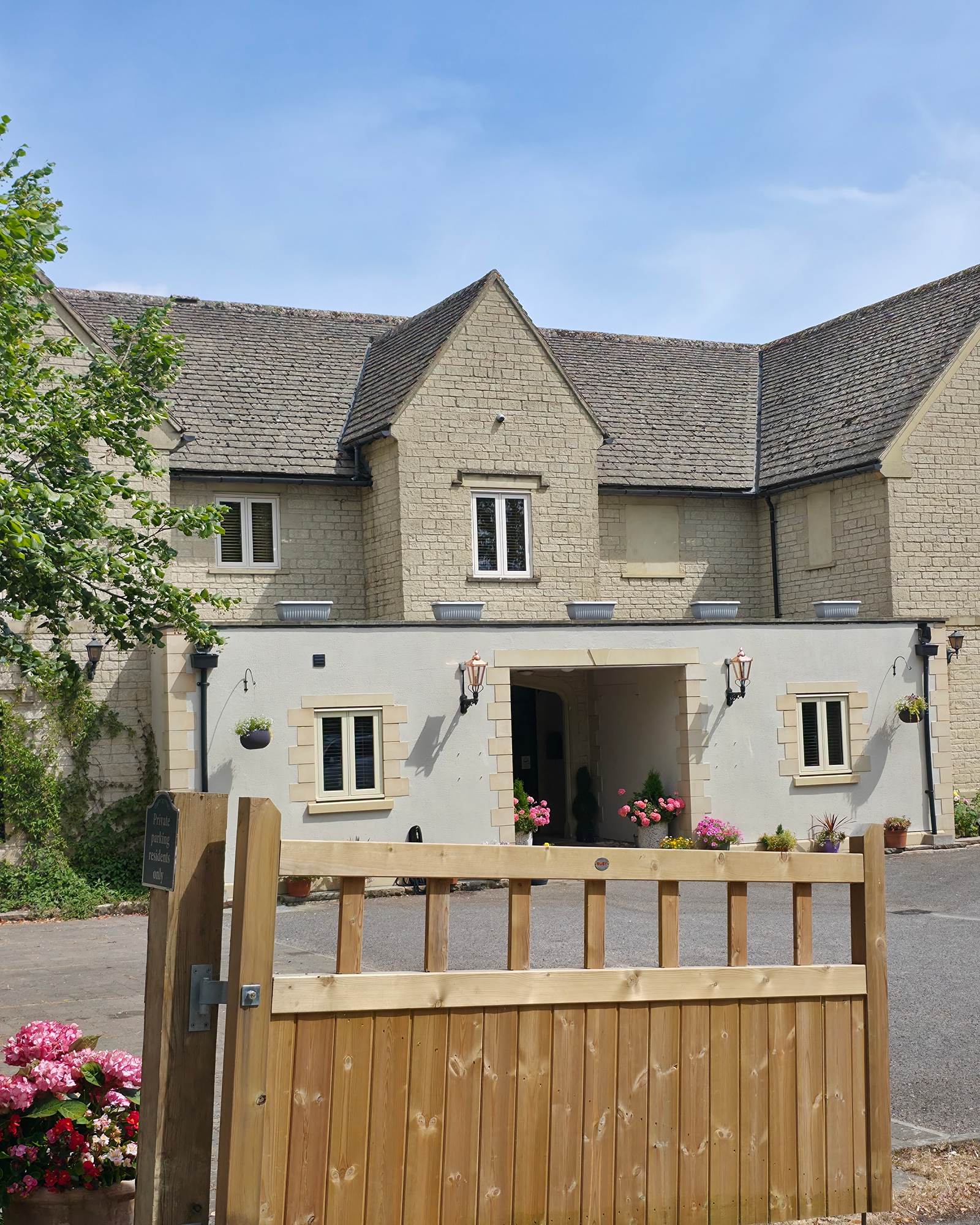 Timber gate and lamp post in front of a stone building with porch entrance