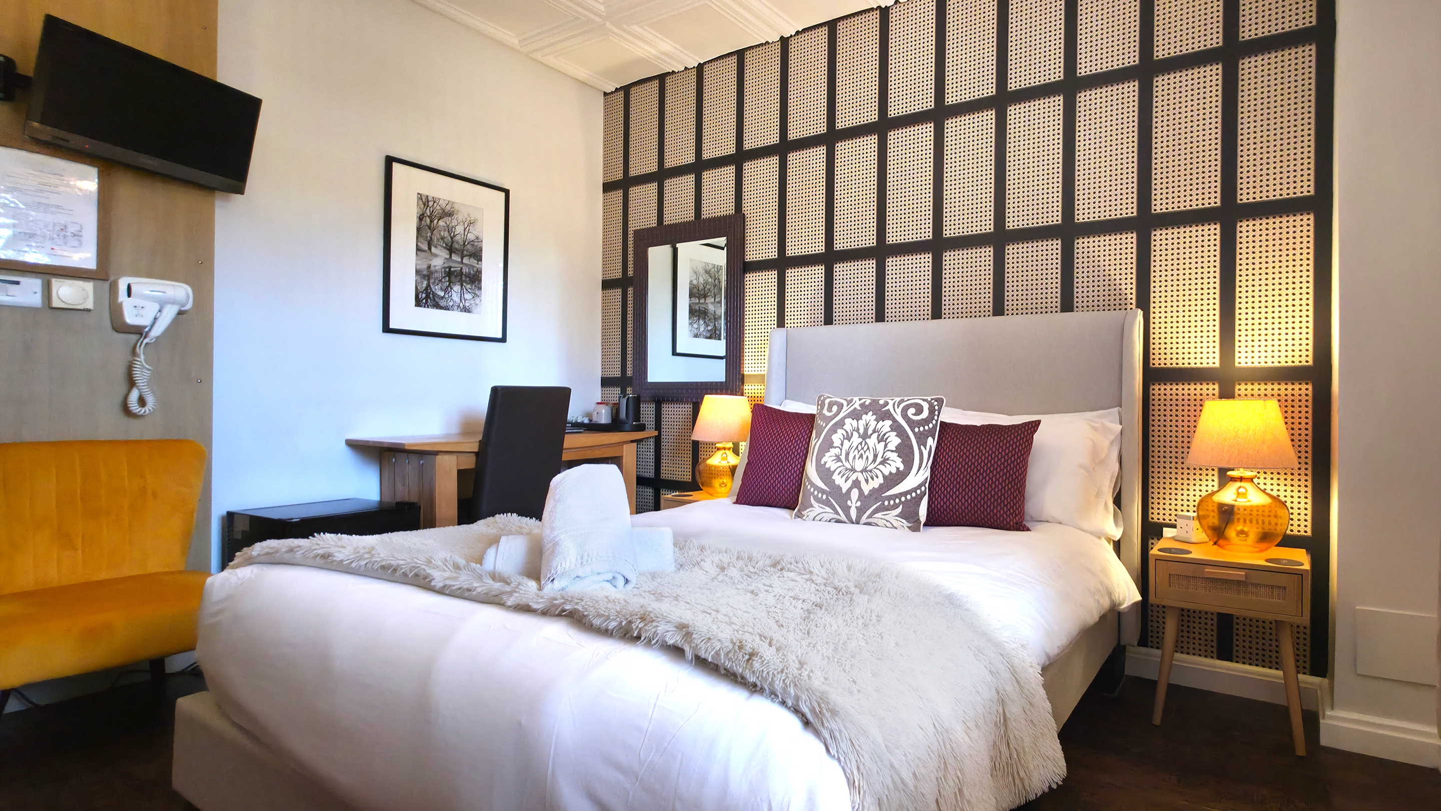 Double bed with painted arch mural behind, oak wardrobe and window with blind