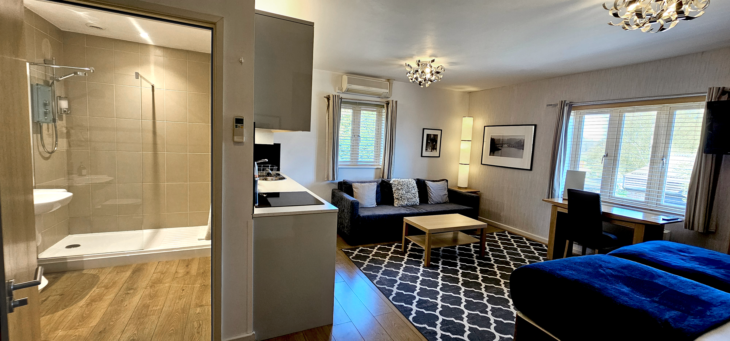 Twin Studio Suite with sofa, coffee table, desk, TV,  kitchenette & doorway to bathroom & walk in shower