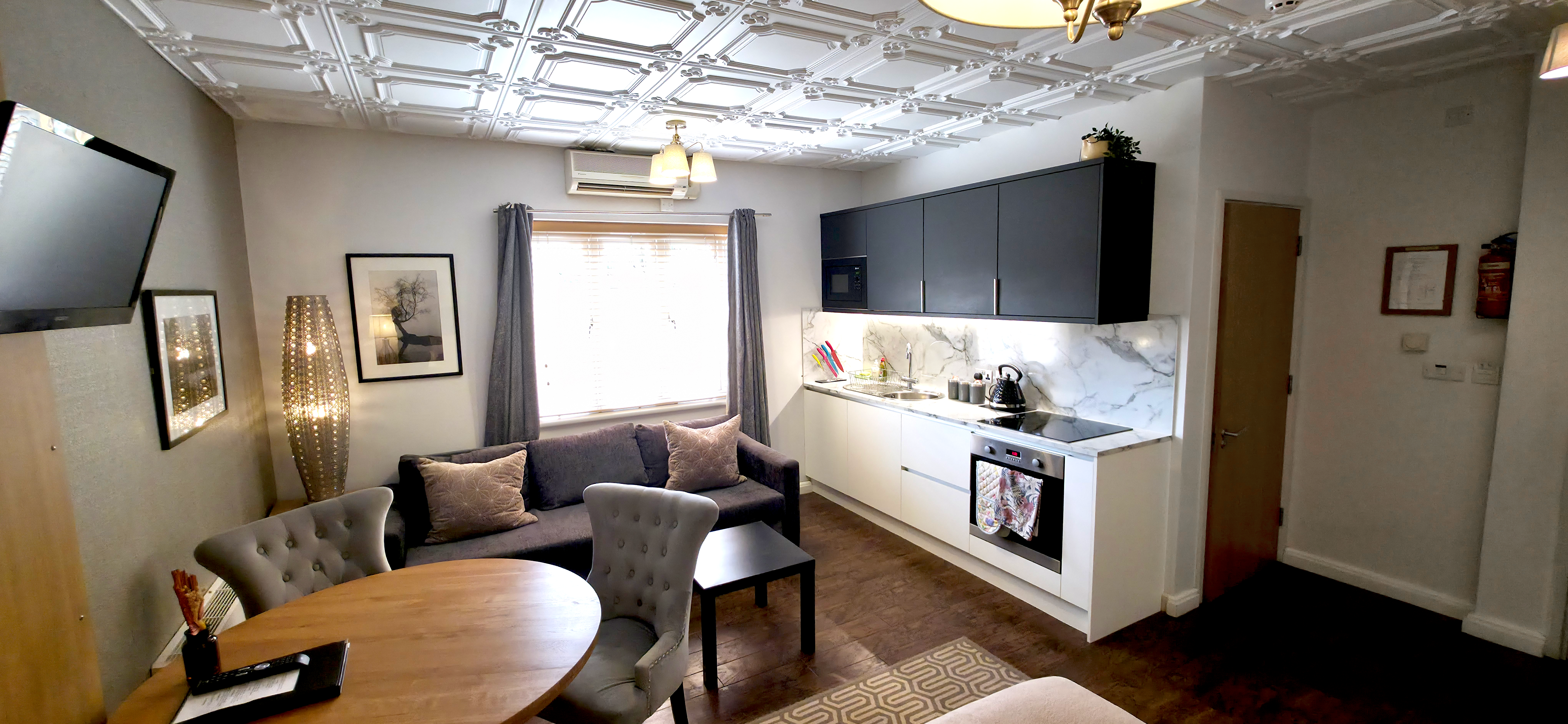 Fitted kitchenette with oven & hobs, sofa, dining table TV & door to ensuite bathroom