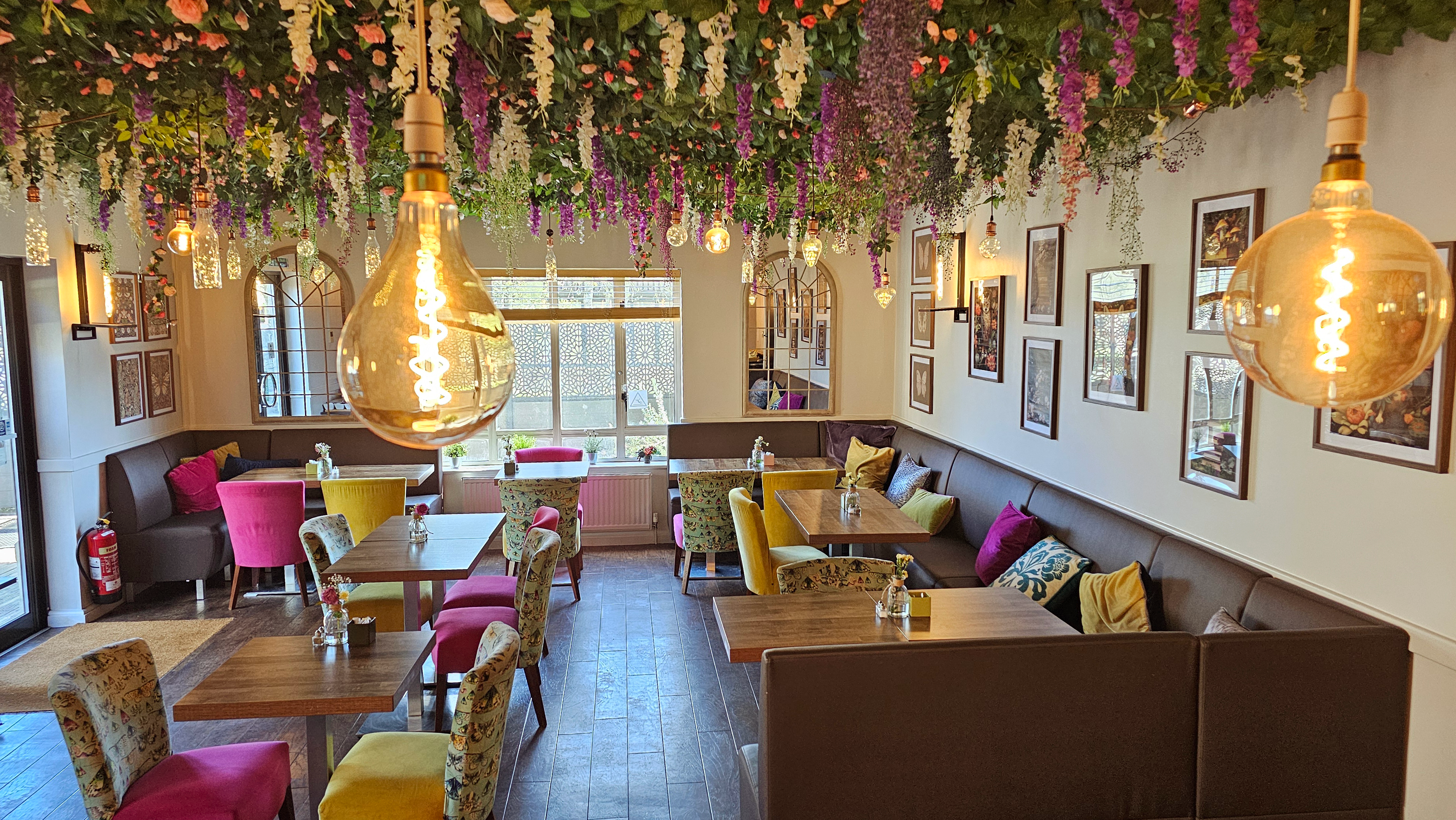 Dining area with banquette seating an&d coloured chairs under a floral ceiling display