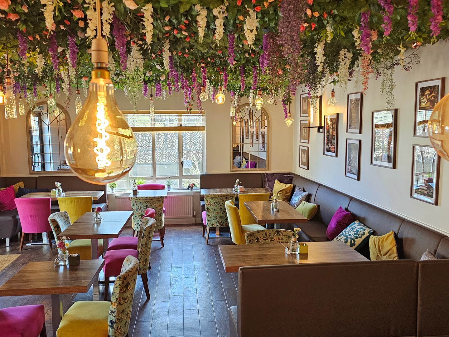 Dining area with banquette seating an&d coloured chairs under a floral ceiling display