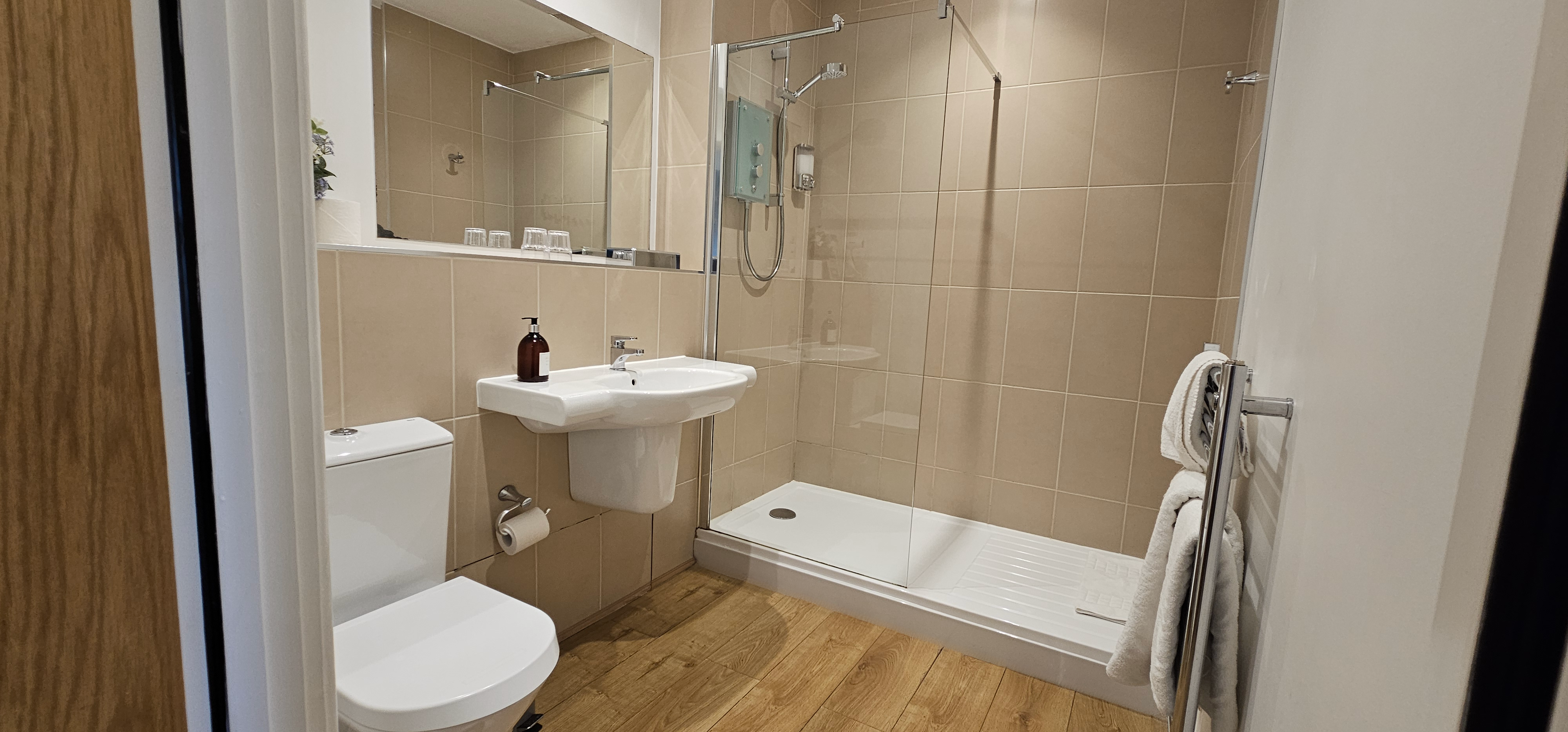 Large ensuite bathroom - walk in shower with glass screen beside a basin & heated towel rail