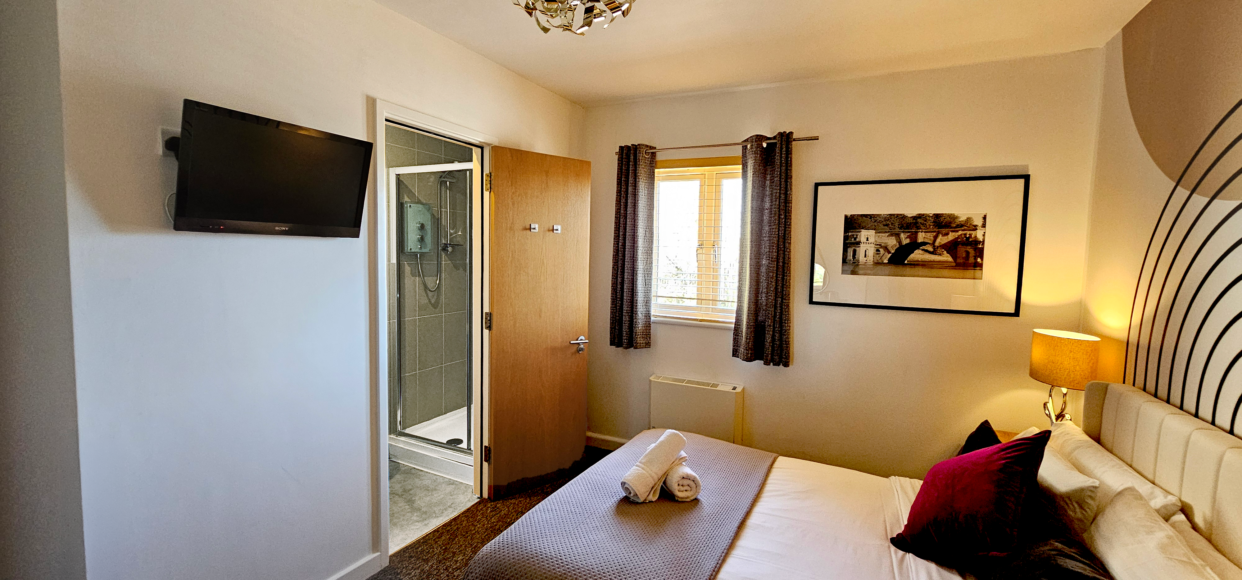 Double room with rolled towels facing open shower & bathroom with digital TV