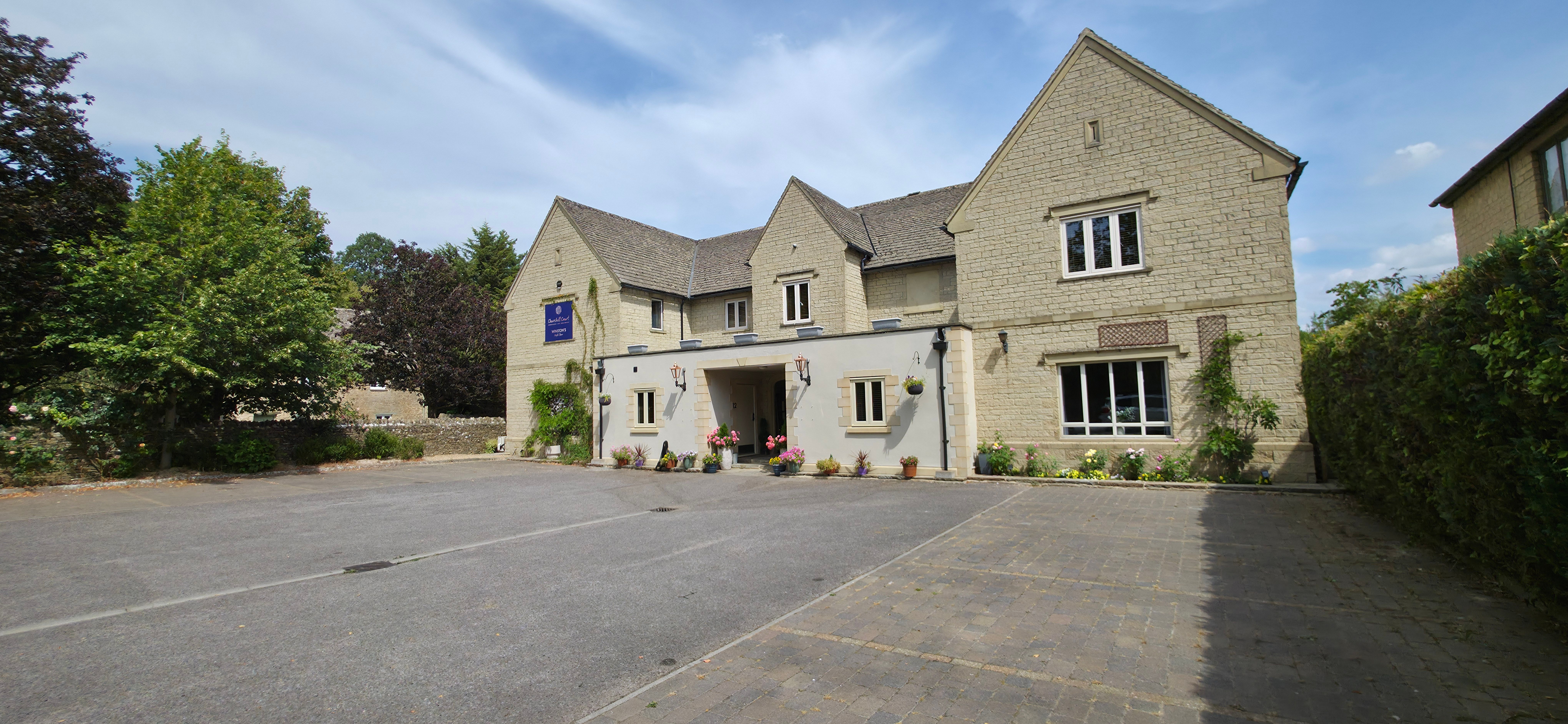 Stone building with a covered entrance and planters beside the parking area