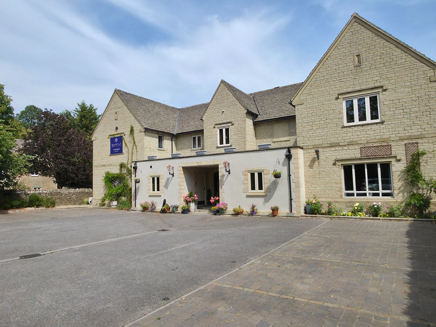 Stone building with a covered entrance and planters beside the parking area
