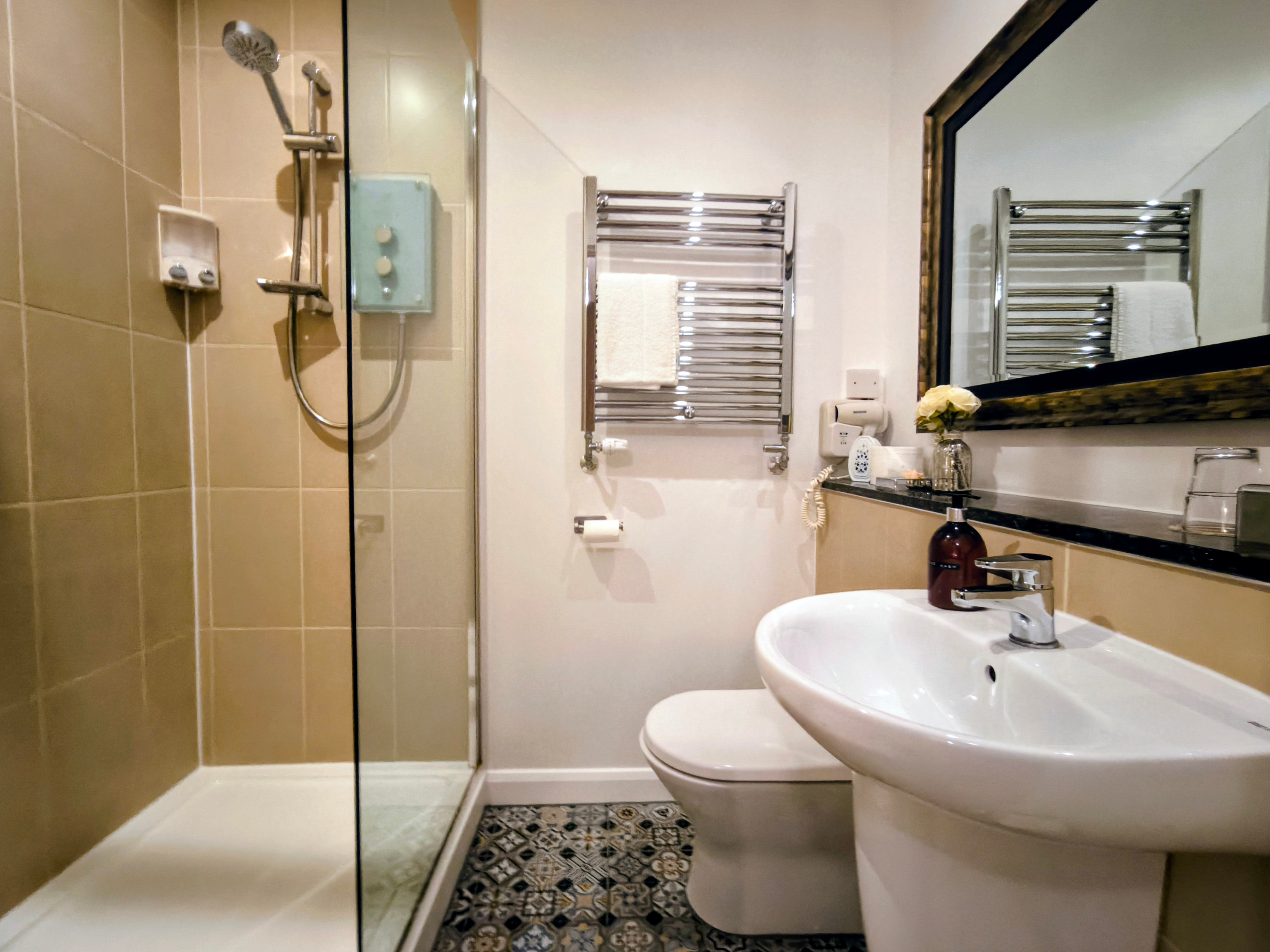 Mosaic & tiled ensuite bathroom with shower cubicle with glass screen & chrome heated towel rail